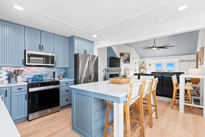 Una cocina moderna con armarios azules, electrodomésticos de acero inoxidable y una isla central con taburetes de bar.