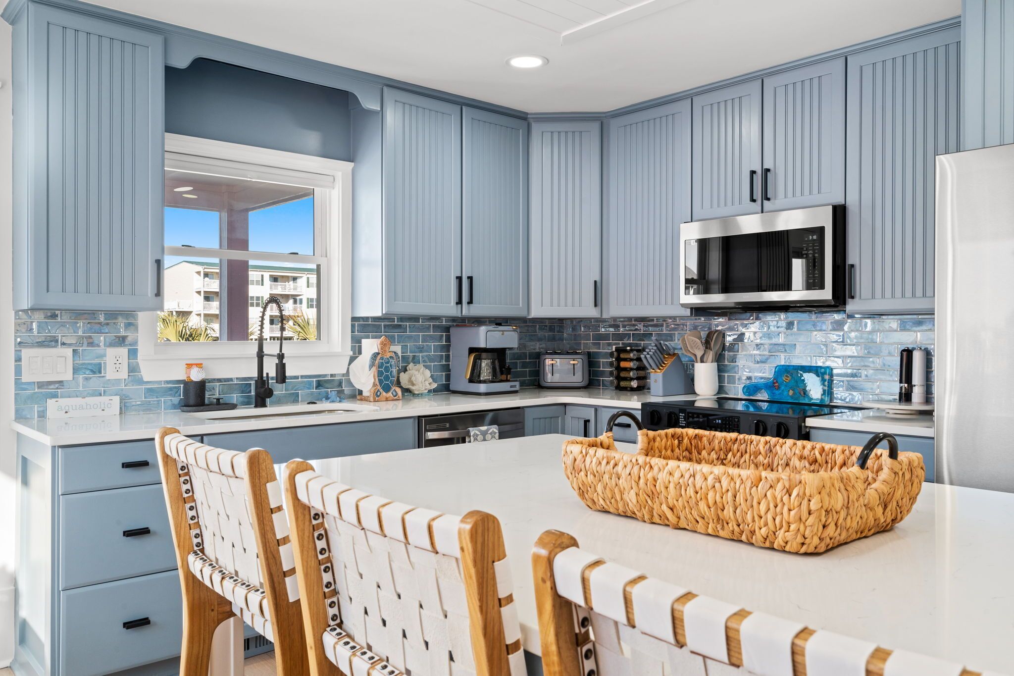 Une cuisine moderne avec des meubles bleus, un îlot central blanc et un four à micro-ondes.