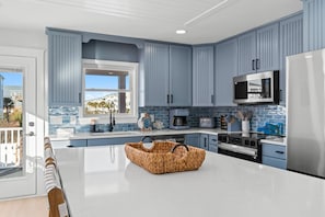 Una cocina moderna con armarios azules, una isla central, un microondas y un refrigerador de acero inoxidable.