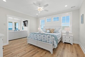A bedroom with a bed, nightstands, a ceiling fan, and windows.