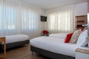 Two beds, a flat-screen TV, and a wooden nightstand are featured in this stylish room.