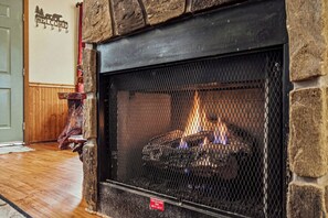 A stone fireplace with a metal screen, a wooden bench, and a welcome sign on the wall. - FREE Dollywood ticket! cozy cabin for up to 4 w/ hot tub, arcade, deck, Wi-Fi (Sevierville)