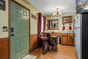 Una cocina con armarios de madera, un lavamanos, un refrigerador y un taburete de madera.
