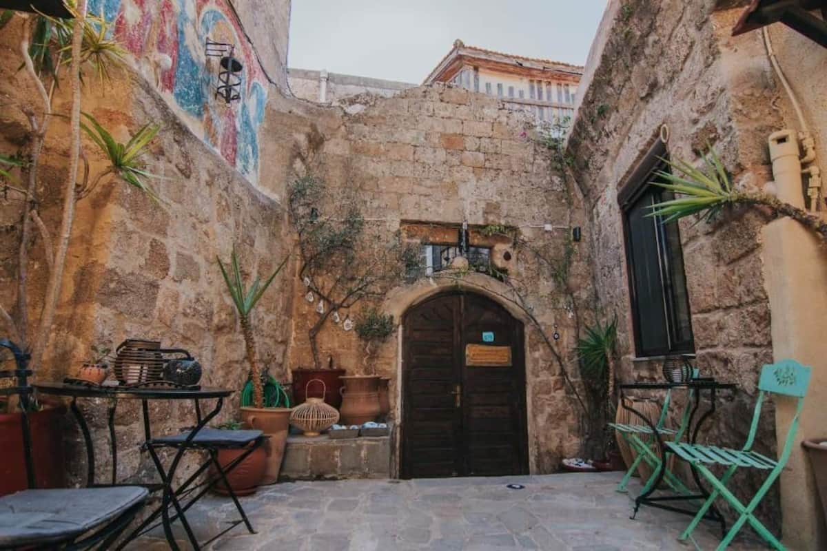 A courtyard with stone walls, a wooden door, and outdoor furniture.