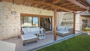 Un espace extérieur aménagé, abrité et doté de mobilier en osier, avec un mur en pierre en arrière-plan.