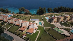 Vue aérienne d  ’une station balnéaire comprenant plusieurs villas, une piscine centrale et une vue sur la mer.