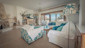 Un salon spacieux avec une cheminée, un téléviseur et une vue sur la mer.