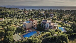 A large villa with a swimming pool, surrounded by lush greenery and a view of the sea. - Thea II Sea View Private Pool Villa, Nikiti (Nikiti)