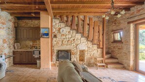 Un intérieur rustique avec une cheminée en pierre, des poutres en bois et une vue sur l’extérieur.