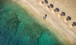 An aerial view of a beach with clear water, a boat, and several umbrellas. - Aminess Planet Camping Holiday Homes Sirena (Novigrad)
