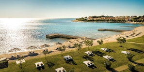 An aerial view of a coastal resort with a sandy beach, lounge chairs, and umbrellas. - Aminess Planet Camping Holiday Homes Sirena (Novigrad)