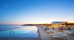 An infinity pool with a view of the sea, lounge chairs, and a building with a bar. - Aminess Planet Camping Holiday Homes Sirena (Novigrad)