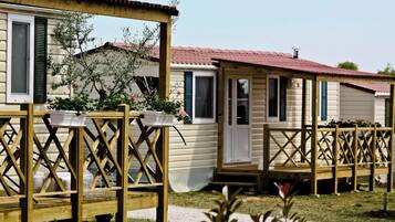 Una hilera de casas móviles con barandillas de celosía de madera y un césped.