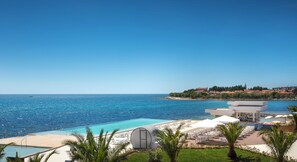 A resort with a swimming pool, lounge chairs, and a view of the sea and distant buildings. - Aminess Planet Camping Holiday Homes Sirena (Novigrad)