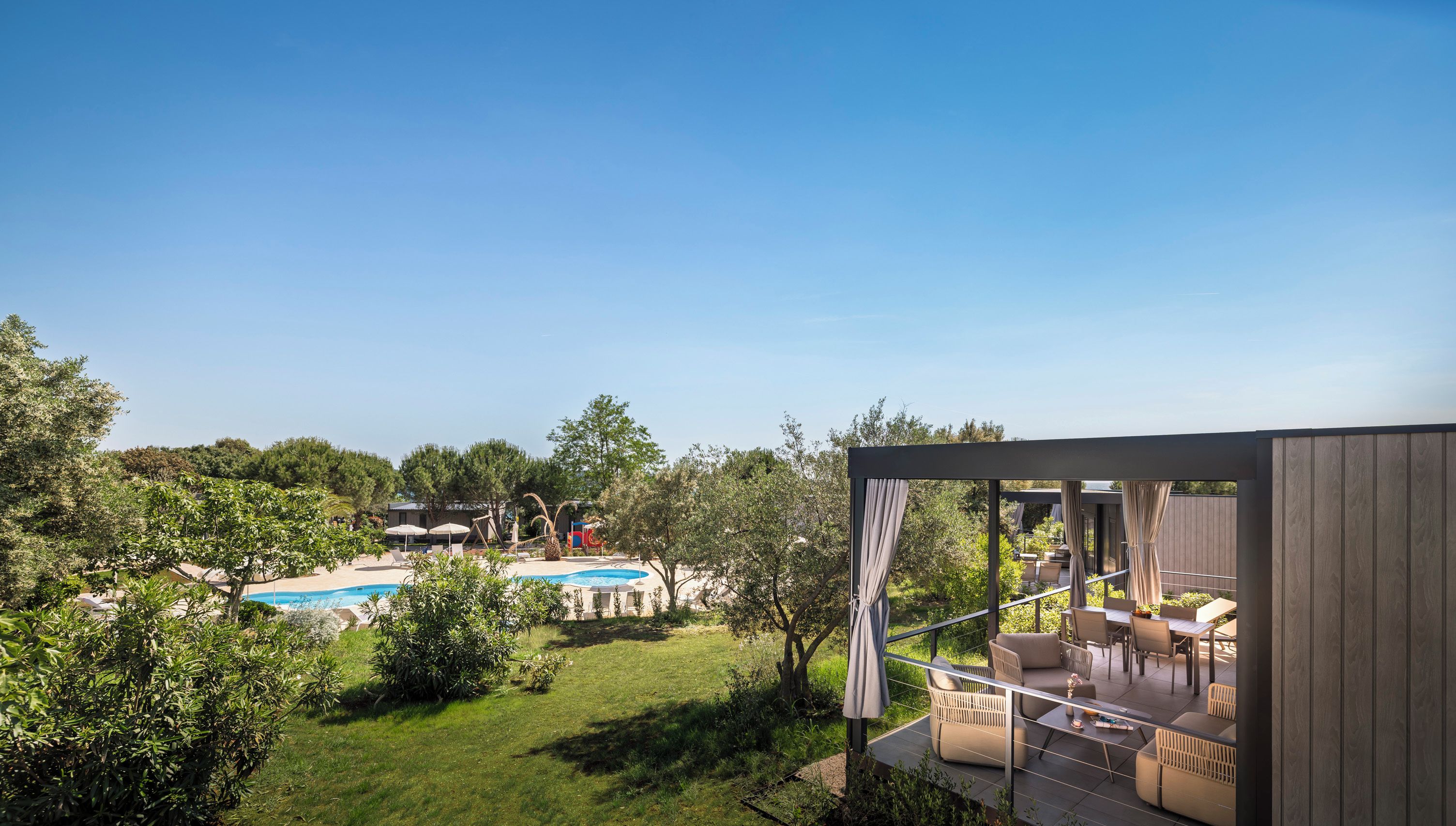 Eine moderne Außenpatio mit Pool, umgeben von üppiger Vegetation und Bäumen.