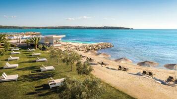 A beach resort with sun loungers, umbrellas, and a pool.
