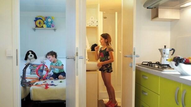 A room with a bed, a child's play area, and a kitchen area with a stove and sink. - Aminess Planet Camping Holiday Homes Sirena (Novigrad)