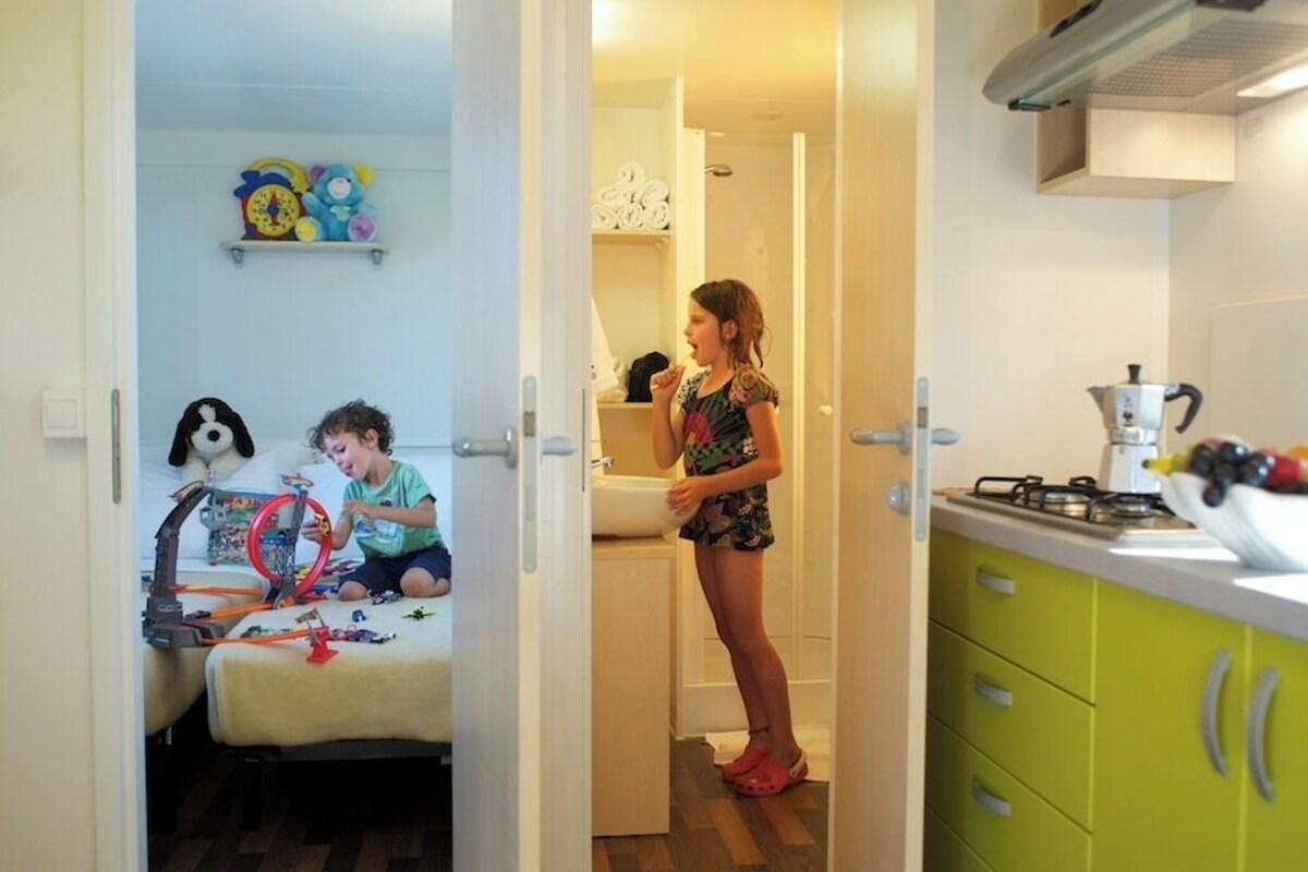 A room with a bed, a child's play area, and a kitchen area with a stove and sink.