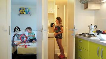 Una habitación con una cama, un área de juegos para niños y una cocina con estufa y fregadero.