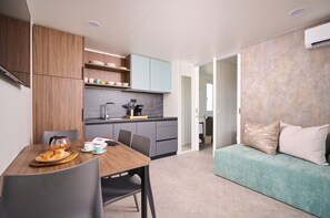 Eine moderne Küche mit grauen Schränken, einem Holzespeisetisch mit Stühlen und einem blaugrünen Sofa im Wohnbereich.