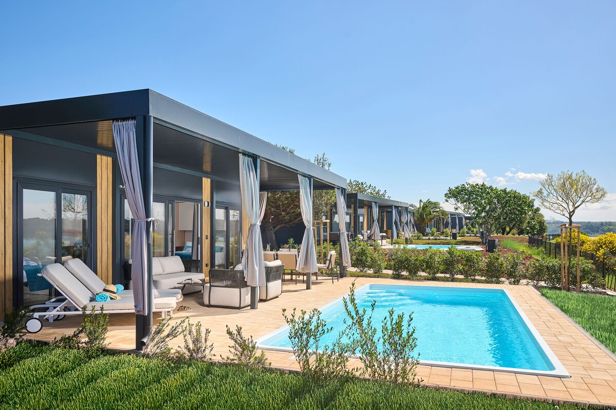 A modern outdoor pool area with lounge chairs and a covered seating area.