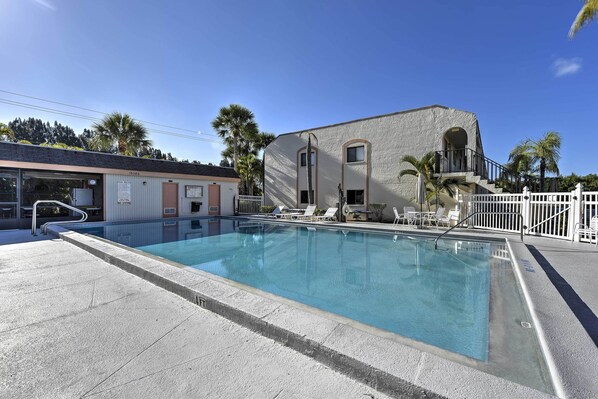 Une piscine avec des chaises longues et un bâtiment doté d’un balcon.