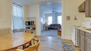 A spacious living area with a dining table and chairs, a kitchen with cabinets and appliances, and a ceiling fan.