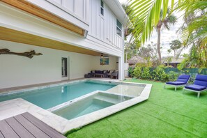 A swimming pool with a wooden deck, a lounge area with blue chairs, and a view of a house with a white exterior and a wooden ceiling. - Walk to Ocean: Home w/ Pool in Holmes Beach (Holmes Beach)