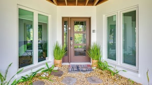 A modern entrance with a wooden ceiling, a brown door, and a welcome mat. - Walk to Ocean: Home w/ Pool in Holmes Beach (Holmes Beach)