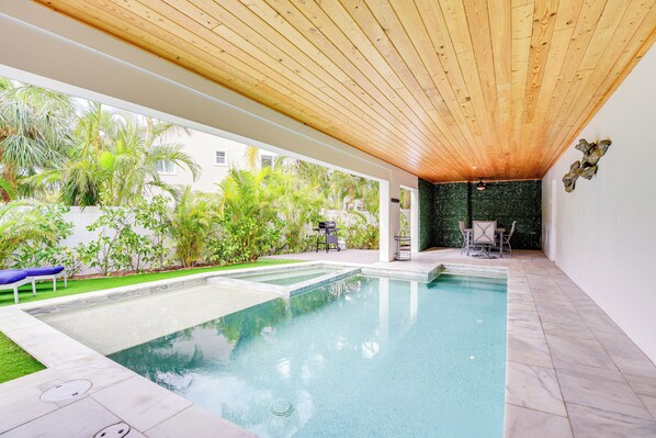 A swimming pool with a wooden ceiling, surrounded by greenery and a patio area with outdoor furniture. - Walk to Ocean: Home w/ Pool in Holmes Beach (Holmes Beach)