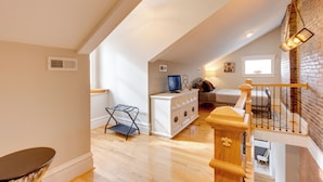 A spacious loft with high ceilings, a wooden staircase, and a cozy seating area with a television. - Walkable Area: Spacious Apt in Dtwn St Louis (St. Louis)