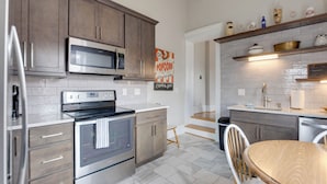 A modern kitchen with stainless steel appliances, wooden cabinets, and a tiled backsplash. - Walkable Area: Spacious Apt in Dtwn St Louis (St. Louis)