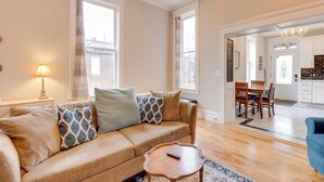 A living room with a beige sofa, patterned cushions, a wooden coffee table, and a blue rug. - Walk to Anheuser-busch Brewery: St Louis Escape! (St. Louis)