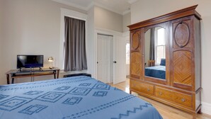 A bedroom with a bed, a wooden wardrobe, a television on a desk, and a door with curtains. - Walk to Anheuser-busch Brewery: St Louis Escape! (St. Louis)