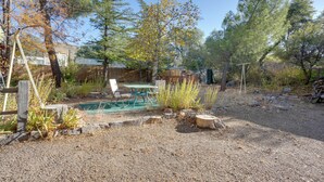 Un jardin avec une piscine, une terrasse en bois et une zone délimitée par une clôture.