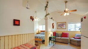 Une pièce confortable avec un lit, deux canapés, une table à manger et un ventilateur de plafond.
