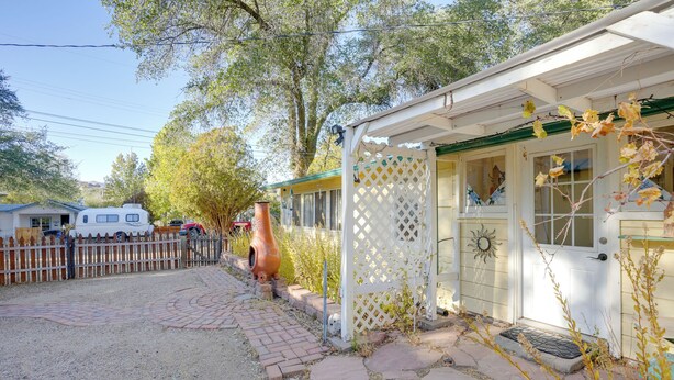 Une cabane rustique dotée d’une véranda, d’une cour clôturée et d’un grand vase.