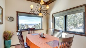A dining area with a table set for four, large windows, a chandelier, and a clock on the wall. - 4 Mi to Black Canyon: Mtn-view Apt in Montrose! (Montrose)