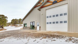 A building with a large garage door, a stone entrance, and a gravel driveway. - 4 Mi to Black Canyon: Mtn-view Apt in Montrose! (Montrose)