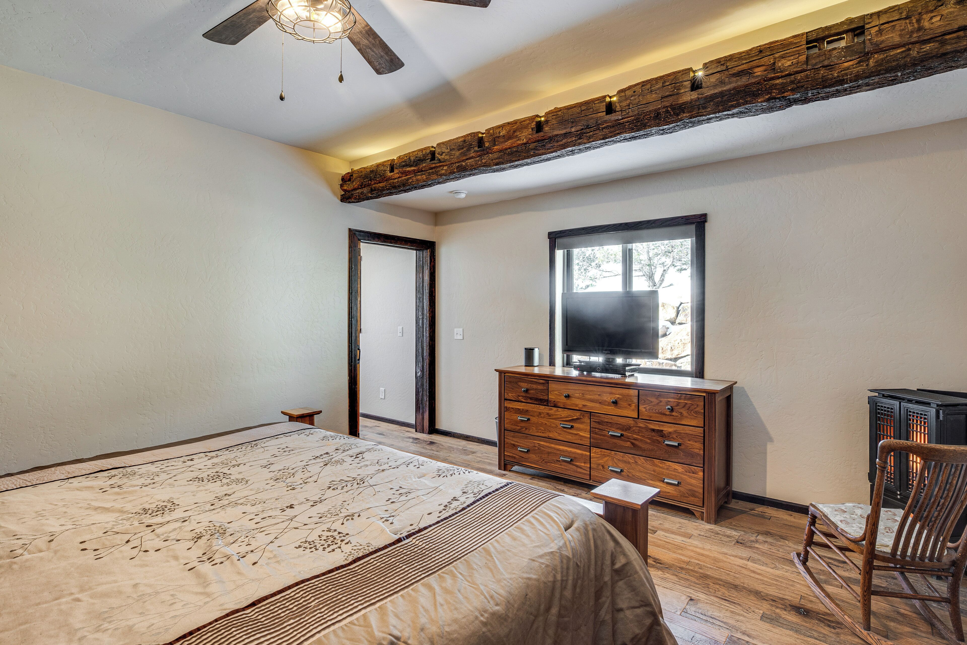 Une chambre à coucher avec un grand lit, une commode en bois et un téléviseur.