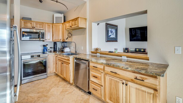 A modern kitchen with wooden cabinets, stainless steel appliances, granite countertops, and a built-in oven. - 4 Mi to Black Canyon: Mtn-view Apt in Montrose! (Montrose)