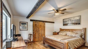 A bedroom with a wooden bed, a desk with a computer, a ceiling fan, and a painting on the wall. - 4 Mi to Black Canyon: Mtn-view Apt in Montrose! (Montrose)