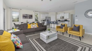 Een moderne woonkamer met een grijze bank, gele fauteuils en een witte salontafel.