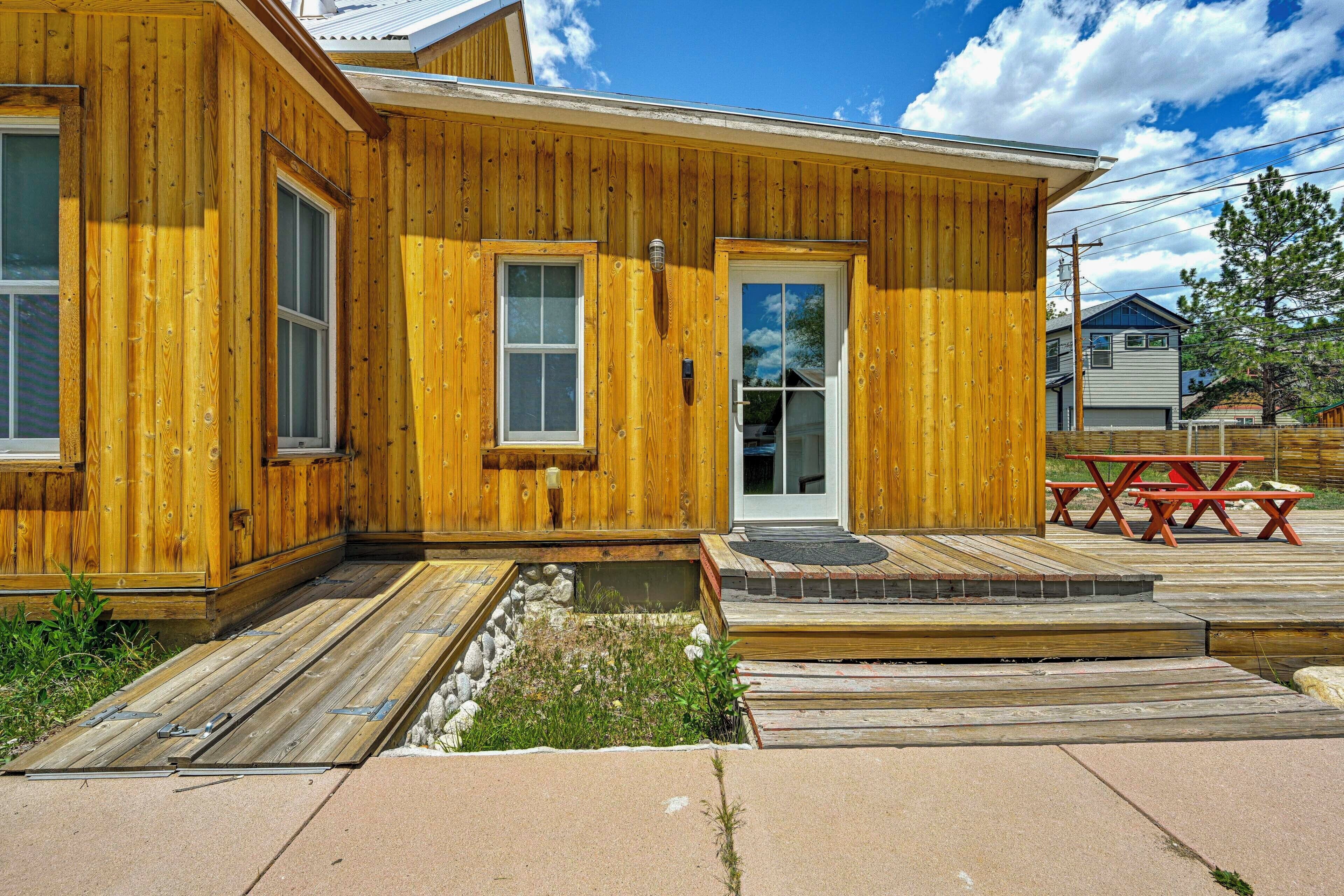 A wooden cabin with a front porch, a small garden area, and a picnic table.