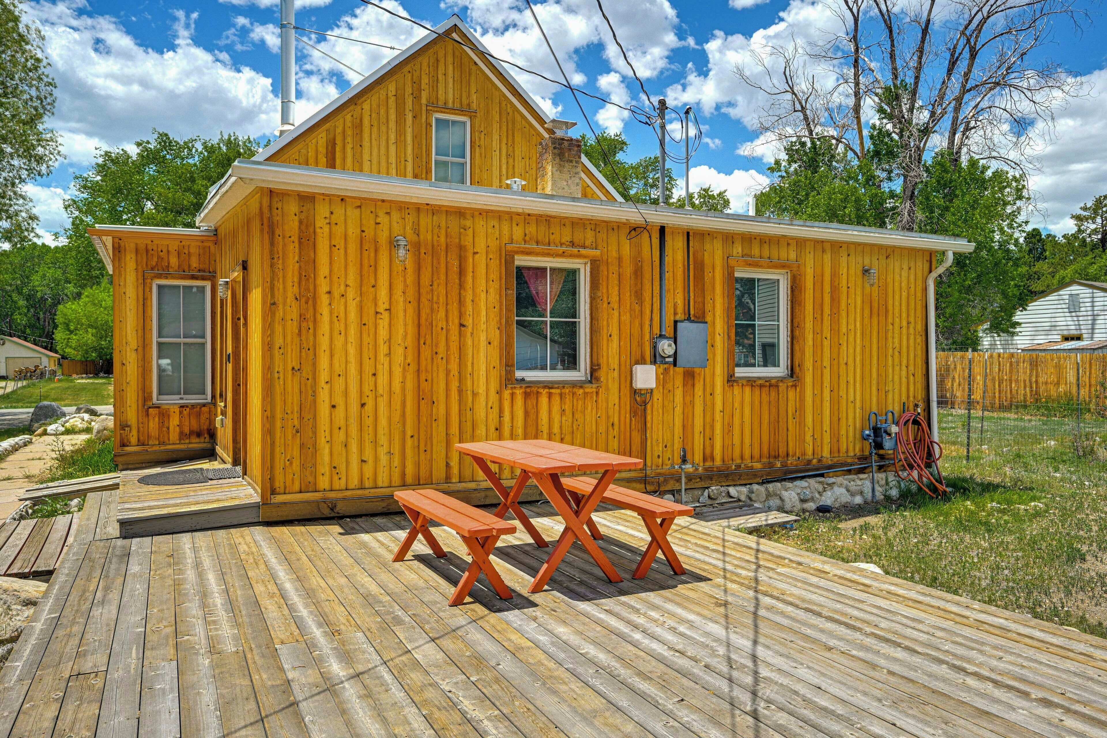 Une cabane en bois dotée d’une terrasse, d’une table de pique-nique et de bancs.