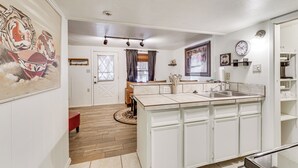 A modern kitchen with white cabinetry, a central island, and a dining area with a wooden table and chairs. - Walk to Angel Fire Resort: Condo w/ Furnished Deck (Angel Fire)