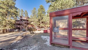 A lodge with a wooden exterior, a bear sign, and a view of a forested area. - Walk to Angel Fire Resort: Condo w/ Furnished Deck (Angel Fire)