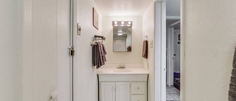 A narrow bathroom with a white sink, mirror, and towel rack.