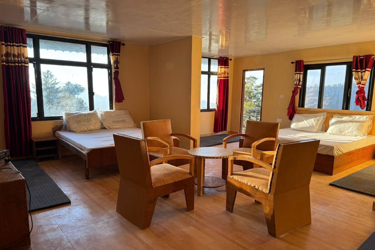 A cozy room with a bed, two chairs, a small table, and a desk.