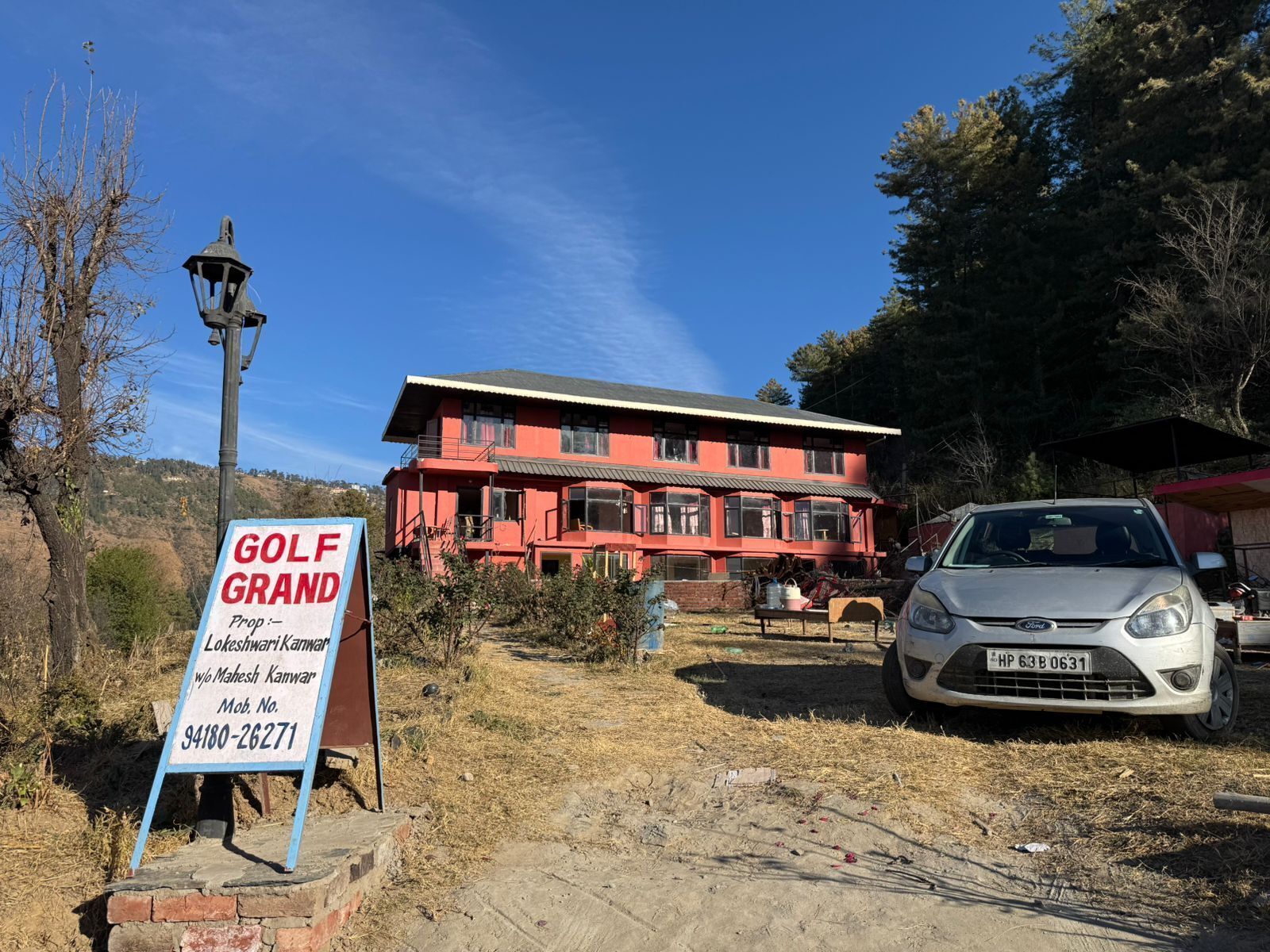 A red building with a signboard for 'GOLF GRAND' and contact details.